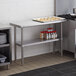 A Regency stainless steel work table with an undershelf holding a tray of food.