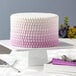 A white cake on a white plate with purple and white icing decorated using the Wilton Lace Silicone Fondant Mold.