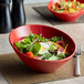 A GET crimson melamine bowl filled with salad with egg and tomatoes on a table.