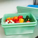 A green plastic container with vegetables in it.