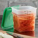 A translucent Cambro square container with carrots in it.