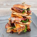 A stack of Rich's par-baked oval flatbread sandwiches with meat and vegetables on a plate.