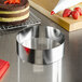 A stainless steel round cake mold filled with a cake on a table with strawberries on top.