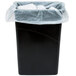 A black trash can with a white plastic bag over it.