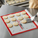 A person cutting cookies on a Fat Daddio's rimless anodized aluminum cookie sheet.