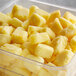 A plastic container of IQF pineapple chunks on a counter.