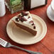 A slice of chocolate pie on a tan Acopa Foundations narrow rim melamine plate with a fork next to it.
