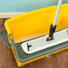 A yellow Lavex Microfiber mop in a Lavex mop bucket.