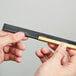 A person holding a black and gold Unger ErgoTec squeegee blade.
