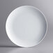 An Acopa Lunar white melamine plate with a white rim on a gray background.