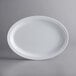 An Acopa Foundations white melamine oval platter on a gray surface.