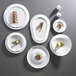 A group of white Corona porcelain plates with food on them.