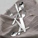 A group of Fortessa Grand City stainless steel demitasse spoons on a cloth.