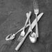 A close-up of Fortessa Ringo stainless steel salad/dessert forks on a grey surface.