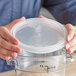 A person holding a Vigor translucent plastic lid over a clear container.