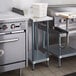 A kitchen with a Regency stainless steel equipment filler table on a counter.