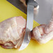 A Mercer Culinary breaking knife cutting a chicken.