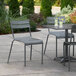 A Lancaster Table & Seating matte gray powder coated aluminum outdoor side chair on a patio.
