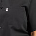 A close up of a man wearing a black Uncommon Chef cook shirt with a pocket.