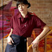 A woman wearing a burgundy Uncommon Chef cook shirt leaning on a wooden handrail.