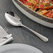 An Acopa stainless steel serving spoon next to a dish of pasta.