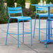 A blue Lancaster Table & Seating outdoor barstool on a patio.