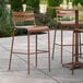 Three brown Lancaster Table & Seating outdoor barstools on a patio.