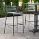 A Lancaster Table & Seating outdoor barstool on a patio with a table and chairs.