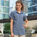 A woman in a steel gray short sleeve Uncommon Chef cook shirt smiling with her hands on her hips.