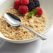 A bowl of oatmeal with berries and an Acopa stainless steel teaspoon.