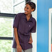 A smiling woman in a Uncommon Chef eggplant purple cook shirt.