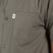 A person wearing an olive green Uncommon Chef cook shirt with a pocket.