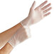 A pair of hands wearing Noble Products clear vinyl gloves.