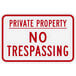 A white rectangular aluminum sign with "Private Property / No Trespassing" in red text.