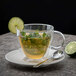 A Villeroy & Boch Artesano Barista double wall glass cup with tea and a lime wedge on the saucer with a spoon.
