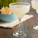 Two Stolzle margarita glasses filled with margaritas on a table.