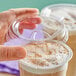 A hand putting a Choice clear plastic sip-through lid on a cup of coffee.