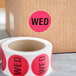 A roll of pink Lavex Wednesday stickers with white labels and black text.