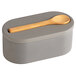 A grey cement salt cellar with a wooden spoon on top.