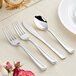 A Visions silver plastic cutlery set on a table with a white plate.