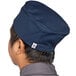 A man wearing a navy blue Uncommon Chef skull cap with a hook and loop closure.