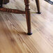 A Master Caster round floor saver on a wooden chair leg on a hardwood floor.