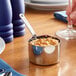 A Vollrath stainless steel mini sauce pan filled with food on a table.