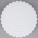 A white plastic Wilton cake separator plate with scalloped edges.