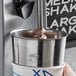 A hand using a Mercer Culinary stainless steel malt cup collar to mix a malt.