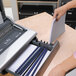 A person using a Fellowes Galaxy electric comb binding machine to bind a book.