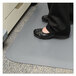 A person standing on a Guardian gray anti-fatigue floor mat.