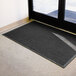 A black Guardian EcoGuard wiper mat on the floor in front of a door.