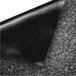 A black fabric corner on a grey surface of a Guardian pepper/salt wiper mat.