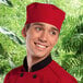 A smiling man in a black chef's jacket wearing a red Uncommon Chef skull cap with a hook and loop closure.